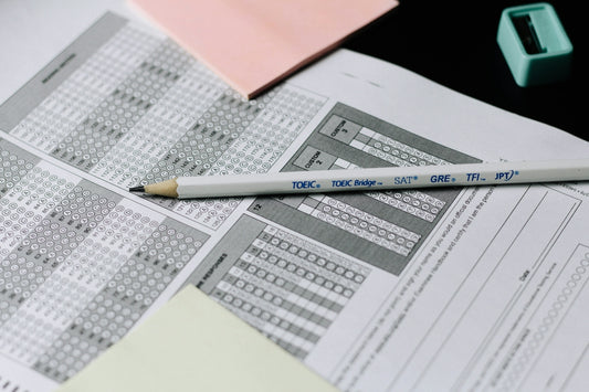 A pencil resting on a multiple choice answer sheet with pink sticky notes